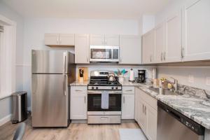 a kitchen with white cabinets and a stainless steel refrigerator at Renovated 1BR, Washington Sq, Longwood, Green Lin in Brookline