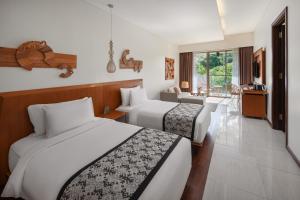 a hotel room with two beds and a living room at MERUSAKA Nusa Dua in Nusa Dua