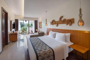 a bedroom with a large bed and a living room at MERUSAKA Nusa Dua in Nusa Dua