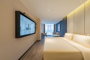um quarto de hotel com uma cama e uma televisão de ecrã plano em Atour Hotel Beijing Guomao Tuanjie Lake em Pequim