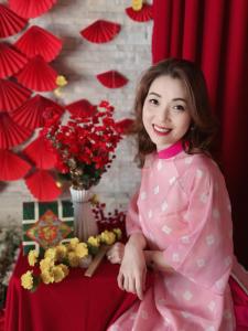 una ragazza con un vestito rosa in piedi accanto a un tavolo con dei fiori di Phương Anh Valley Hotel a Da Lat