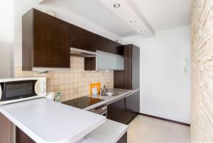 a kitchen with brown cabinets and a white counter top at Prokocim Podłęska Studio in Krakow