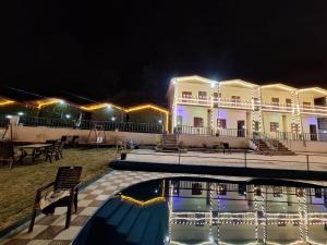 a resort with a swimming pool at night at Haveli Resort in Rishīkesh