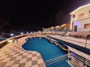 a swimming pool at night with a checkered floor at Haveli Resort in Rishīkesh