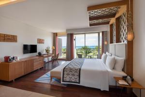 a hotel room with a bed and a television at MERUSAKA Nusa Dua in Nusa Dua