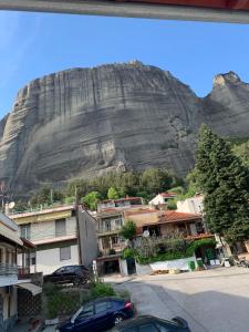 a mountain in the background with houses and cars at Pirinas Meteora in Kalabaka