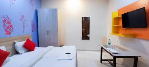 a bedroom with a bed with a desk and a tv at Roomshala 002 Rose Residency Near Yashobhoomi in New Delhi