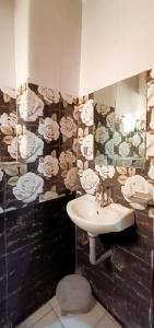 baño con lavabo y papel pintado de flores en Roomshala 002 Rose Residency Near Yashobhoomi en Nueva Delhi