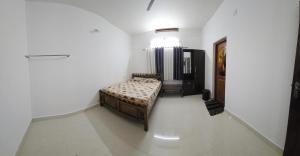 a bedroom with a bed in a white room at Meadow Heaven Home Stay in Munnar