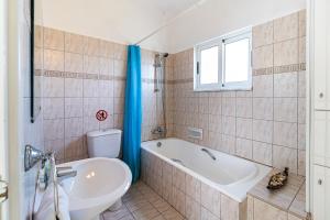 a bathroom with a tub and a toilet and a sink at Ayia Thekla Serenity Villa in Ayia Napa