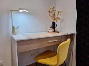 uma secretária com uma cadeira amarela e um espelho em Chambre GUSTAV em Agen