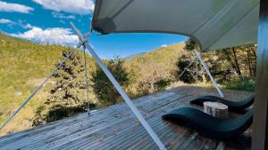 a porch with swings and an umbrella on a deck at 九寨沟阿布氇孜民宿Jiuzhaigou Valley Abluzi B&B in Jiuzhaigou