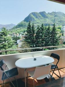 una mesa blanca y sillas en un balcón con montañas en Sailing Apartment Lugano, en Lugano