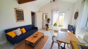 ein Wohnzimmer mit einem blauen Sofa und einem Tisch in der Unterkunft Charmante maisonette au calme in Léon
