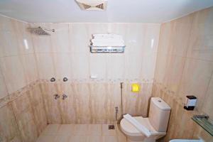 a bathroom with a toilet and a shower with towels at Hotel Central Inn & Spa in Dhaka