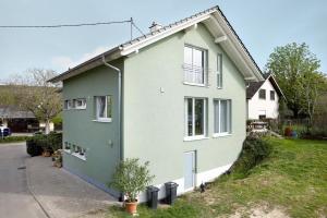 a green and white house with a driveway at Ferienwohnung In Der Weinig in Sasbach am Kaiserstuhl