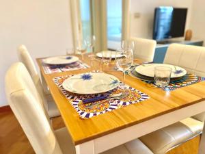 ein Holztisch mit Tellern und Weingläsern darauf in der Unterkunft Appartamento con posto auto riservato tra spiaggia, centro, stazione ed ospedale in Pescara