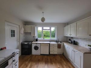 a kitchen with white cabinets and a washer and dryer at Carrigaline Delightful Home in Carrigaline