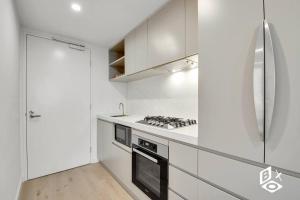 een keuken met witte kasten en een kookplaat oven bij REST COLLECTION Highrise Studio Apartment at Melbourne Central in Melbourne