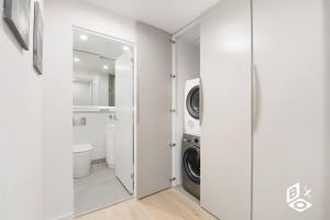 een witte wasruimte met een wasmachine en droger bij REST COLLECTION Highrise Studio Apartment at Melbourne Central in Melbourne +25 foto's