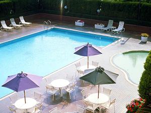 a swimming pool with tables and umbrellas next to it at Art Hotel Kagoshima in Kagoshima