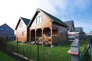 een houten huis met een hek in een tuin bij Nowabobolin domki in Bobolin