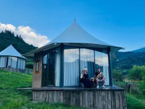 two people sitting in a tiny house in a field at 九寨沟阿布氇孜民宿Jiuzhaigou Valley Abluzi B&B in Jiuzhaigou