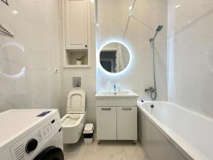 een witte badkamer met een wastafel, een bad en een toilet bij Esil Riverside Elite Apartments in Astana