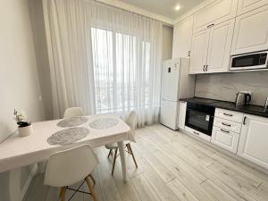 eine weiße Küche mit einem Tisch und Stühlen im Zimmer in der Unterkunft Esil Riverside Elite Apartments in Astana