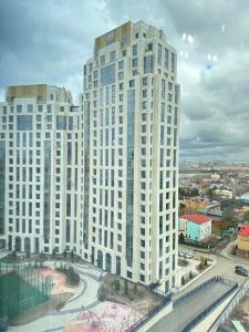 een hoog wit gebouw met een straat ervoor bij Esil Riverside Elite Apartments in Astana