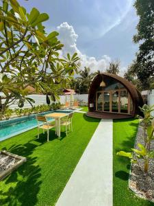 un jardín con mesa y sillas junto a una piscina en Found Mansion, en Pantai Cenang