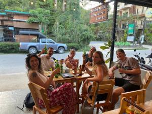 um grupo de pessoas sentadas à mesa com bebidas em Flora Hostel KhaoSok em Khao Sok