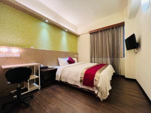 a hotel room with a bed and a desk and a television at Zhao Lai Hotel in Kaohsiung