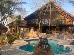 a house with a statue in front of a pool at Ivory Sands Safari Lodge in Marloth Park