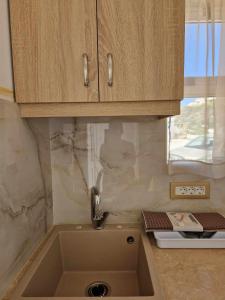 eine Küchentheke mit einem Waschbecken und einem Fenster in der Unterkunft Christina Studios in Kefalos