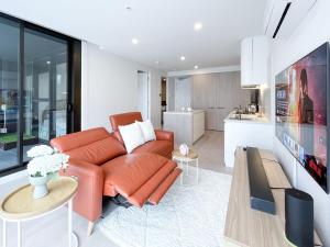 sala de estar con sofá naranja y cocina en Modern Luxury 2B2B Sky Garden SmartTV, en Glen Waverley