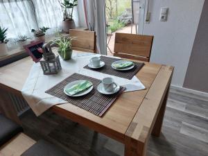 a wooden table with two cups and plates on it at Ferienwohnung Leute in Tengen