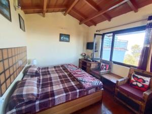 a bedroom with a bed and a chair and a window at Vineet's homestay in Mukteshwar