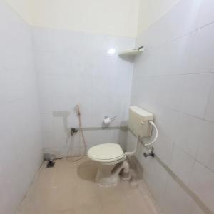 a white bathroom with a toilet in a room at Mount Paradise guest house in Tiruvannāmalai +2 photos