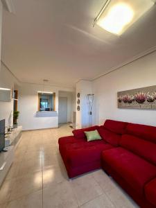 a living room with a red couch and a television at Atardecer en Torre la Sal in Castellón de la Plana