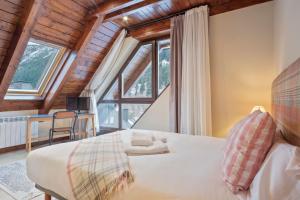 a bedroom with a bed and a large window at Luderna - Dúplex Val de Ruda C10 Estanh Redond in Baqueira-Beret