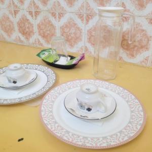a table with two plates and a glass vase at Mount Paradise guest house in Tiruvannāmalai