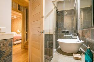 uma casa de banho com uma banheira e uma cabina de duche ao nível do chão em Luderna - Tríplex Tuc dera Salana em Tredós