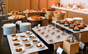 a buffet line with plates of food and desserts at Shilla Monogram Quangnam Danang in Hoi An