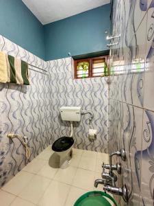 La salle de bains est pourvue de toilettes, d'une fenêtre et de murs bleus. dans l'établissement Sajeev Home Stay, à Cherai Beach