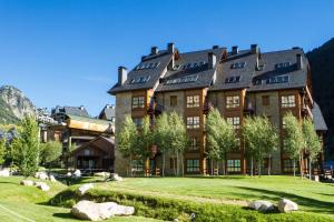 a large building in the mountains with a green lawn at Luderna - Apartamento Val de Ruda B14 Paulet in Baqueira-Beret