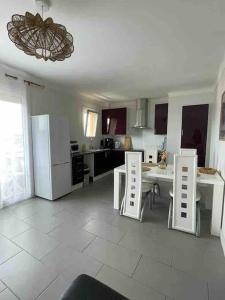 eine Küche mit einem Tisch und Stühlen sowie einem Kühlschrank in der Unterkunft Au QALM in Canet-en-Roussillon