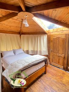 ein Schlafzimmer mit einem Bett in einem Holzzimmer in der Unterkunft Quinde Ñan Lodge in Papallacta