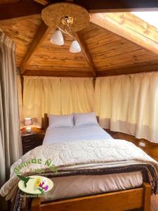 a bed in a room with a wooden ceiling at Quinde Ñan Lodge in Papallacta