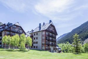 a large building in a grassy field next to a mountain at Luderna - Apartamento Val de Ruda A5 Orla in Baqueira-Beret